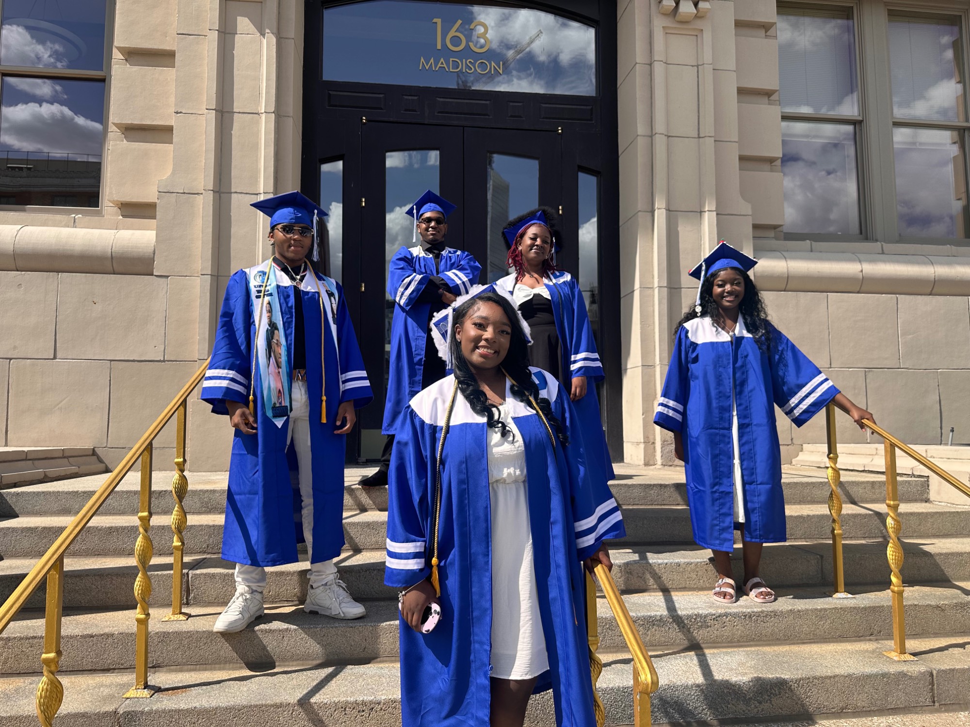 Students posing in graduation regalia in front of of the GVSU Detroit Center